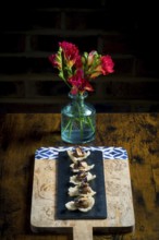Elegant cracker canapes topped with vegetable satay stew and peanuts, served on a black slate over