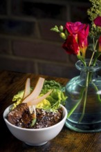 A beautifully presented Asian beef bowl garnished with fresh greens and pear slices, paired with a