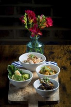 Bowls featuring chicken with glass noodles and peanuts, broccoli and cauliflower in satay sauce,