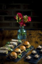 Elegant display of vegetable and courgette rolls, pulled pork and cabbage mini burgers, and rare