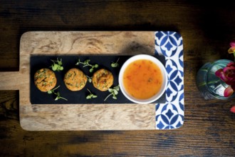 Top-down view of golden corn and spring onion patties served with a bowl of sweet chili sauce,