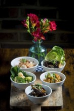 A selection of vibrant Asian cuisine bowls arranged on a wooden board The dishes feature