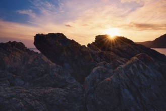 At Cala del Lastre, Portman in Murcia, Spain, a breathtaking sunset casts warm hues over rugged