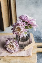 Delicate pink and white chrysanthemums in a glass vase evoke autumnal charm Set against rustic