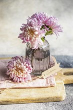 Elegant chrysanthemums in a textured glass vase, set on a wooden board, create an autumnal theme A