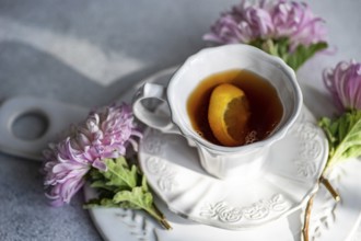 Elegant autumn-themed setup featuring a hot beverage with a lemon slice in a white cup Surrounded
