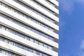 From below geometric view of a modern multi-story building, featuring rows of white balconies