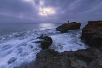 A dramatic seascape view at Cabo Cervera, Torrevieja, Alicante A lone figure stands on rocks,