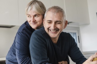 A joyful senior couple shares a tender moment, embracing in their modern kitchen The scene captures