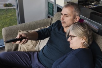 Senior couple relaxing on a comfortable sofa, enjoying a moment together while watching television