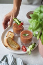 A refreshing summer meal with chilled gazpacho garnished with cucumber, tomato, and basil,