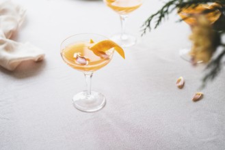 Elegant mandarin cocktail served in a stemmed glass, garnished with a twist of orange zest, on a