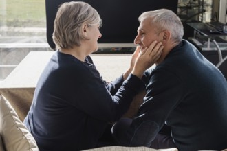 An intimate moment between a senior couple, sitting closely and smiling at each other The warmth