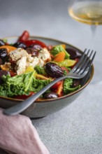 Close-up of a vibrant salad with raw kale leaves, assorted cherry tomatoes, sliced red onions, BBQ