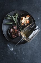Top view of a sophisticated arrangement featuring Greek BBQ olives in a small black bowl, a portion
