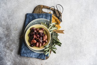 Top view of a rustic-styled bowl filled with Greek BBQ olives on a wooden cutting board with fresh
