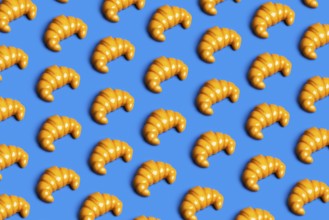 A vibrant pattern of plastic croissants against a blue background, symbolizing the clash between
