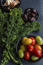 Top view of a healthy salad featuring raw kale leaves, a mix of colorful cherry tomatoes, red onion