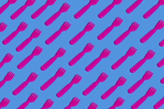A vivid pattern of pink plastic forks on a blue background highlights the critique of junk food