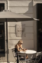 Bratislava, Slovakia. October 2nd 2023 A Woman sits at a Cafe beside a memorial Plaque outside the