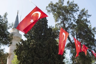 Bodrum, Turkey. April 23rd 2022 Turkish national flag fluttering in front of an Islamic minaret of