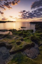 Stunning sunset over the rocky coast of Cabo Roig, Orihuela, Alicante, Spain The sky's warm hues