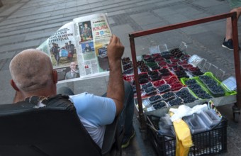 Belgrade, Serbia. July 27th 2019 A Serbian man reading a newspaper while selling fruit on the