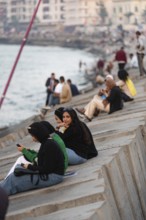 Alexandria, Egypt. December 1st 2022 Young Egyptian women sit on concrete sea defence walls in the