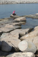 Alexandria, Egypt. December 1st 2022 Muslim women wearing a pink hijab sitting on large concrete