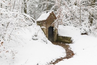 Small water spring with house in snow, Thrarandter Wald, Saxony, Germany