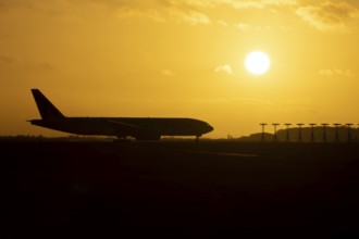 Boeing 777 A7-BFL commercial jet aircraft of Qatar cargo waiting to take off silhouette at sunset