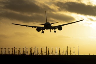 Boeing 777 commercial passenger jet aircraft in flight on approach to land over runway lights