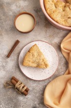 Apple Charlotte cake on brown concrete background and orange linen textile, cup of milk, top view,