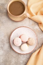 Macarons colourful cookies dessert, cup of coffee, on brown concrete background with orange linen