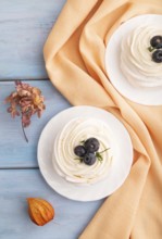 Pavlova Meringue dessert with crisp meringue and blueberry on blue wooden background with orange