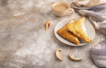 Triangles Pie, Puff Pastry, Samsa with cherry jam on brown concrete background and linen textile,
