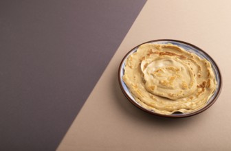 Stack of Plain Fried pancakes on gray and beige pastel paper background. side view, copy space