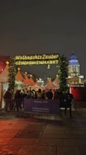 Christmas market at Gendarmenmarkt at night with bright lights and many visitors in a festive
