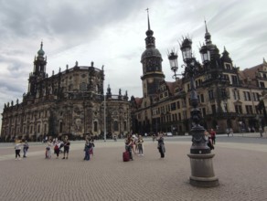 People gather in front of the historic ensemble of buildings in Dresden under a cloudy sky, Dresden