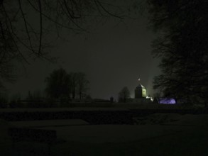 Dark, silent night scene with the dimly lit Rosenberg Fortress behind the trees, Kronach,
