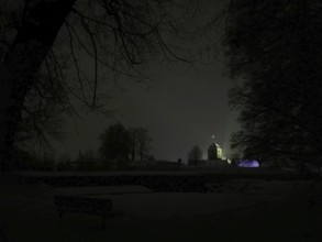 Night view of a dark landscape with a dimly lit, silhouetted Rosenberg Fortress, Kronach,