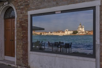 Santa Maria Salute is reflected in a shop window on the island of Guidecca, Venice, Veneto, Italy