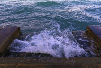 Waves on a staircase, announcement of the Aqua Alta in Venice. Guidecca, Venice, Italy