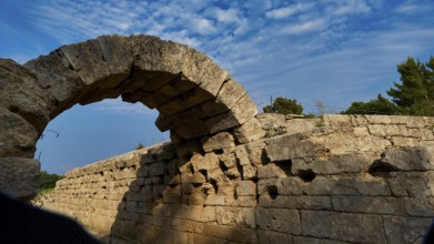 Crypt, vaulted portico, entrance to the stadium, ancient stone arch with shadow cast, surrounded by