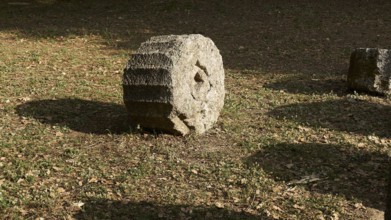 Round stone on earthy soil with surrounding shade, Archaeological Site, Ancient Olympia, Olympia,