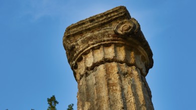 Pillar of Philippeion, head of an ancient stone column with decorated surface against a blue sky,