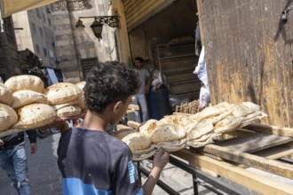 Cairo, Egypt. April 15th 2025. An Egyptian boy delivers baked traditional Baladi flat bread to a
