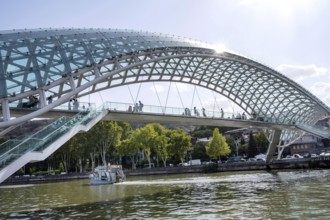 Tbilisi, Georgia. August 26th 2025. Tourists cross The Bridge of Peace over the Kura River also