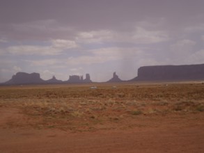 Wide, flat desert landscape with scattered rock formations and cloudy sky, Monument Valley, Navajo