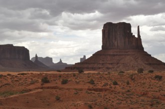 Dramatic view of a large rock formation under a cloudy sky in Monument Valley, Navajo Tribal Park,